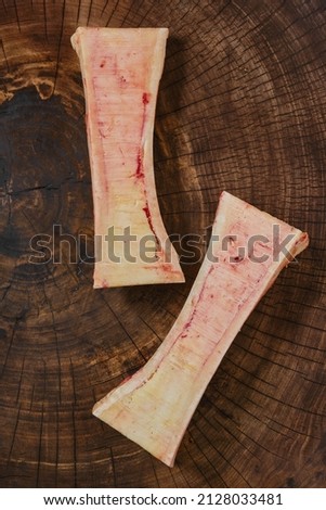 Overhead closeup view of large beef bone marrow chopped on half on wooden stump Royalty-Free Stock Photo #2128033481