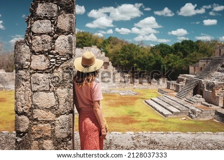 A young woman tourist stands against the backdrop of the Mayan ruins in the ancient city of Edzna.Edzna Campeche Mayan pyramids in Mexico. Travel concept. Royalty-Free Stock Photo #2128037333