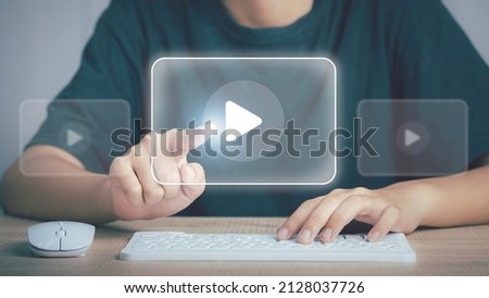 Person using mouse and keyboard watching Video streaming on internet, content online movie or TV ,live concert, show or tutorial on the virtual screen with play button. Royalty-Free Stock Photo #2128037726