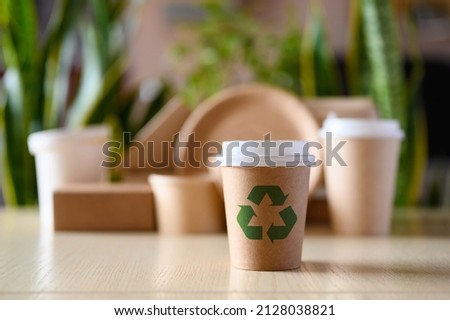Paper cup with a recycling sign on the background of green plants. The concept of using biodegradable materials for the production of dishes to protect the environment. Royalty-Free Stock Photo #2128038821