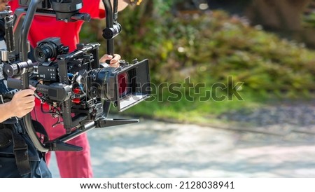 Movie shooting or video production and film crew team with camera equipment. Video camera operator working with equipment. Director of photography with a camera in his hands on the set.	
