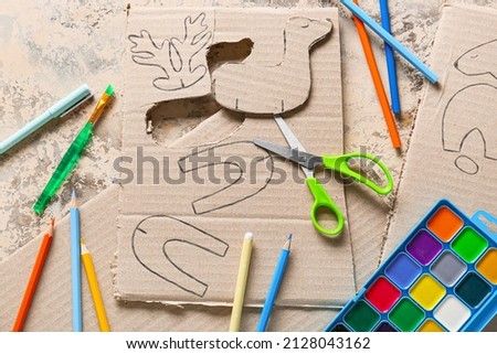 Set of different stationery supplies for handcraft and cardboard toy drawings on grunge background