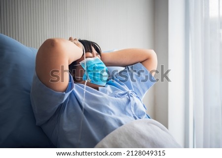 Asian fat woman patients wearing a surgical mask Lying in a patient's bed, having severe headaches, to health care and health insurance concept.