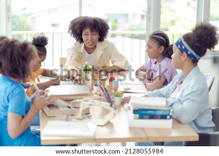 A group of four young African students studying with an African female teacher in a classroom at the school where everyone is studying very hard. This picture is an educational concept.