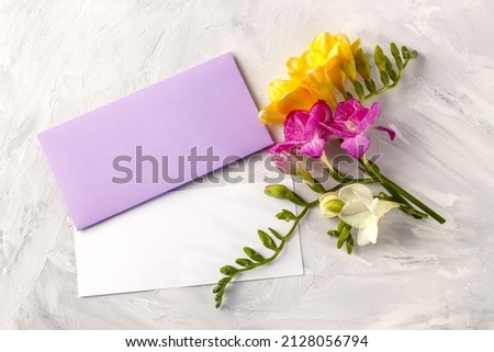 Greeting card mockup with copy space, colorful freesia flowers and greeting envelope on concrete background. Template for branding and advertising Royalty-Free Stock Photo #2128056794