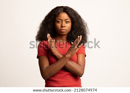Portrait Of Young Black Female Showing Stop Gesture With Crossed Hands, Serious Millennial African American Woman Refusing Something While Posing Over White Studio Background, Copy Space Royalty-Free Stock Photo #2128074974