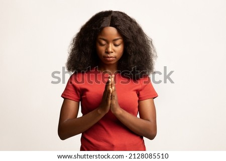 Faith Concept. Portrait Of Calm African American Female Praying With Clasped Hands And Closed Eyes, Religious Young Black Woman Standing Isolated Over White Studio Background, Copy Space Royalty-Free Stock Photo #2128085510