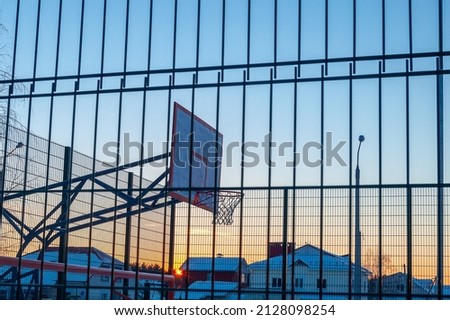 Basketball court at sunset on a cold winter evening. In the background are city cottages. Selective focus