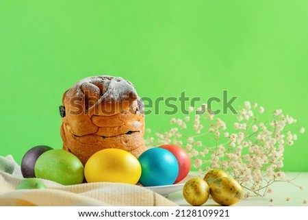 Easter cakes, traditional multi-colored eggs on the festive table, on green background