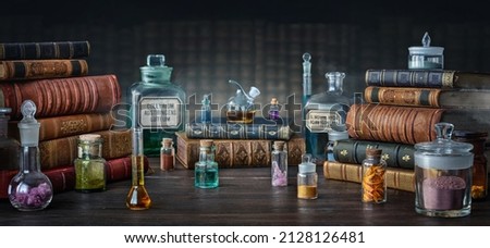 Glass bottles, old books on table of a scientist. Medicine, chemistry, pharmacy, apothecary, alchemy history background. Translation from labels-eyewash astringent, morphine hydrochloride and almonds. Royalty-Free Stock Photo #2128126481