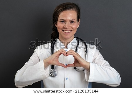 girl doctor in uniform taking care of the heart shows with her hands