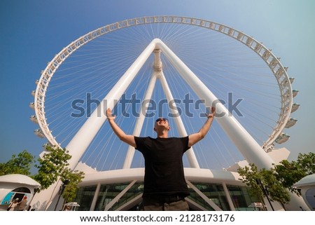 The man tourist threw up her hands in delight at the sight Ain (Eye) DUBAI - One of the largest Ferris Wheels in the World, located on Bluewaters island Royalty-Free Stock Photo #2128173176
