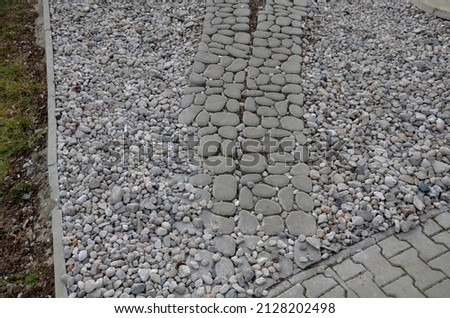 new infiltration parking lot made of aerated concrete tiles in a regular grid with holes filled with pebbles. sidewalk with interlocking paving, pattern of boulders, pebble