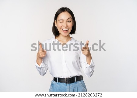 Its you congrats. Smiling attractive asian woman, businesswoman pointing fingers at camera with pleased face, complimenting, inviting you, standing over white background Royalty-Free Stock Photo #2128203272