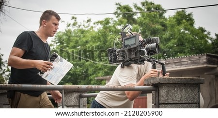 Behind the scenes. Cameraman shooting the film scene with camera on outdoor set. Photography director in movie filmmaking action