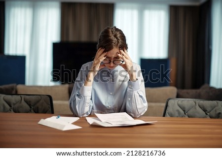 Frustrated stressed young business woman reading paper document, sitting at desk, worrying about tax bill held her head Royalty-Free Stock Photo #2128216736