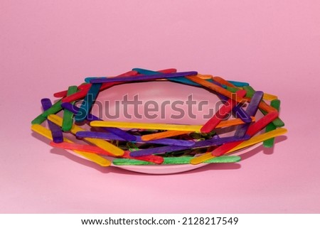 colorful wooden sticks arranged on a pink plate on a pink background creative concept spaceship pink hole