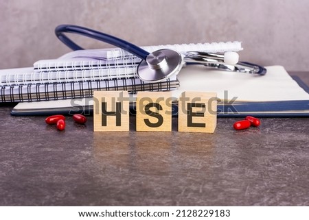 the word hse is written on wooden cubes near a stethoscope on a paper background. medical conceptual word collected of wooden elements with the letters