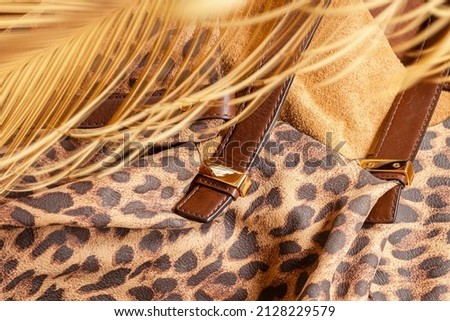 Fashionable handbag from genuine leather embossed under exotic skin of jaguar and tropical palm tree branch, natural tropical background. Shopping concept, fashion accessories