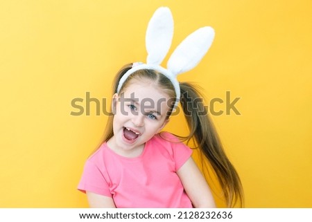 cheerful girl with rabbit ears on her head on a yellow background. Funny crazy happy child. Easter child. Preparation for the Easter holiday. promotional items. copy space for text, mockup
