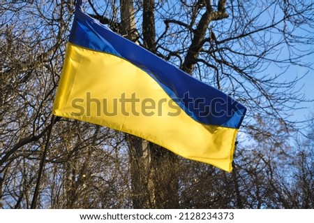 Blue and yellow Ukrainian flag in cloudy sky . High quality photo