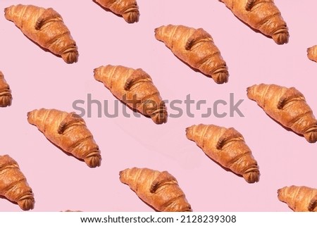 Croissants, traditional French coffee snack. Creative bakery pattern against pastel pink background. 