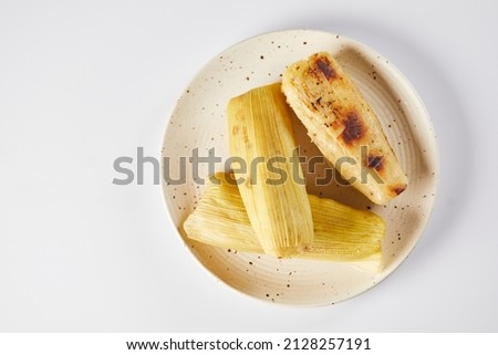 Humitas are savory steamed fresh corn cakes, a traditional Ecuadorian appetizer. On a white background.  Royalty-Free Stock Photo #2128257191