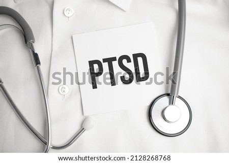 The doctor's blue - gloved hands show the word PTSD - . a gloved hand on a white background. Medical concept. the medicine