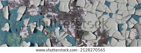 Peeling paint on the wall. Panorama of a concrete wall with old cracked flaking paint. Weathered rough painted surface with patterns of cracks and peeling. Wide panoramic grungy texture for background Royalty-Free Stock Photo #2128270565