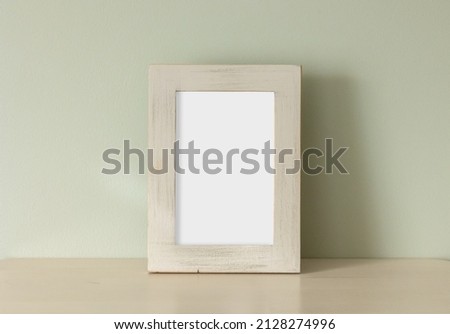 empty frame on table on green wall background