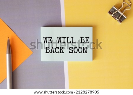 WE'LL BE BACK SOON text on notepad with laptop on the white background