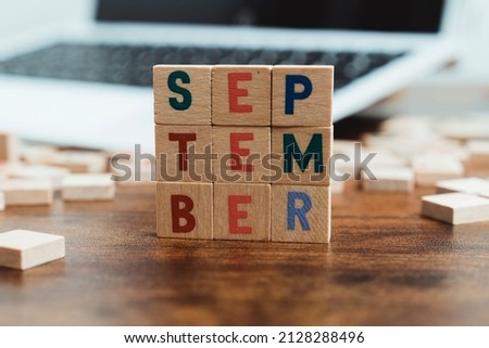The name of the month September written on wooden cubes od the tabletop of th computer desk. High quality photo