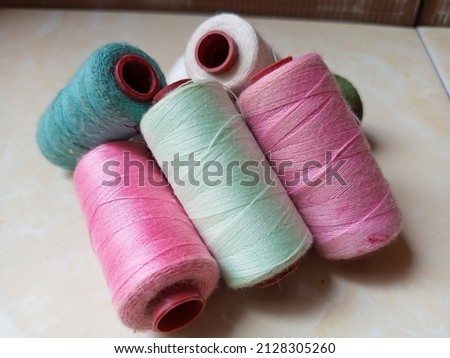 Sewing threads of various colors that sparkle in the sun are arranged in piles.

