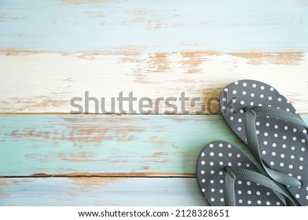 Closeup top view studio shot four pairs travel colorful summertime fashionable rubber flip flops slipper shoes placed on light blue old retro vintage wooden pattern table background with copy space.