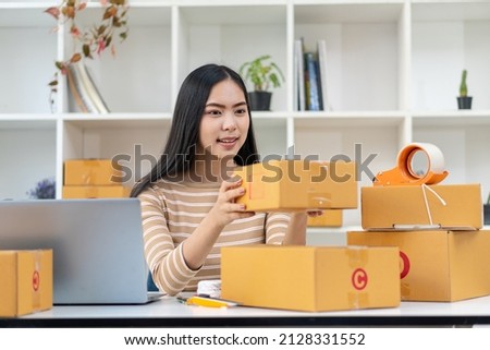 Asian woman working at the home online box with the laptop to take orders from customers, sme parcel delivery business start-up idea.