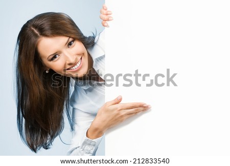 Happy smiling young business woman showing blank signboard, over blue background
