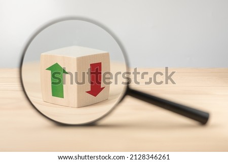 Economy growth and decline analysis. Magnifying glass and wooden cube with green and red arrow. Searching of decisions. Strategy for investors to determine chance to recover after recession