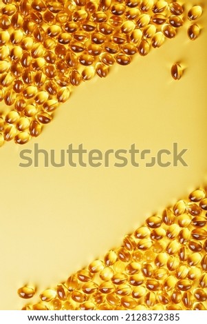 Capsules in a shell with fish oil on a yellow background and a place for text. Golden capsules with a biologically active supplement for health Royalty-Free Stock Photo #2128372385