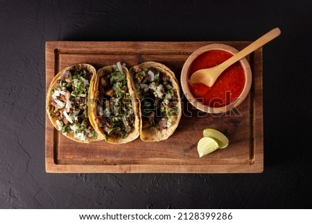 Tacos de Suadero. Fried meat in a corn tortilla. Street food from CDMX, Mexico, traditionally accompanied with cilantro, onion and spicy red sauce 