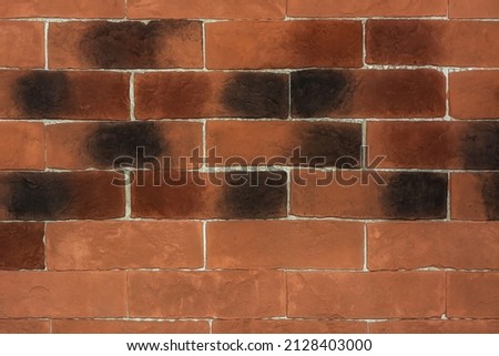 Part of the wall of the building is made of red-brown brick with black spots for use as an abstract background and text.