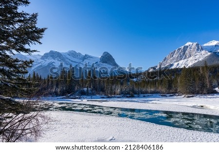 Drift ice floating on Bow River in winter. Clear blue sky, snow capped Mount Lawrence Grassi beautiful landscape. Canmore, Alberta, Canada. Royalty-Free Stock Photo #2128406186
