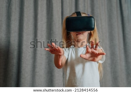 child girl at home in virtual reality VR glasses watching video, playing games. modern children are well versed in technological innovations. generation alpha. High quality photo