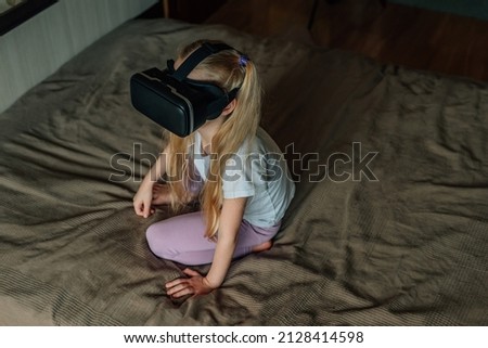 child girl at home in virtual reality VR glasses watching video, playing games. modern children are well versed in technological innovations. generation alpha. High quality photo