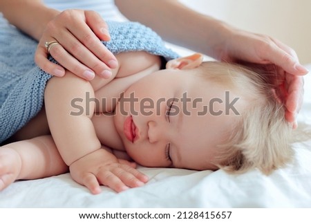 sleeping small child close-up, mother's hands cover a one-year-old baby with a blanket Royalty-Free Stock Photo #2128415657