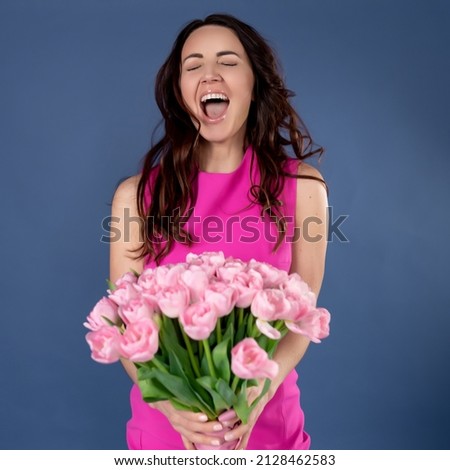 Image of excited happy pretty woman posing isolated on blue background holding flowers