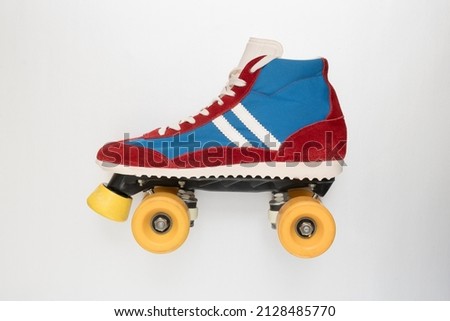 Side view of a roller skate with yellow wheels and blue upper shoe with red leather trim and laces on a white background