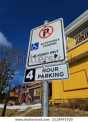 A sign indicating who is allowed to park and for how long. It says no parking, handicap accessible parking in the direction the arrow is pointing, and 4 hour parking.