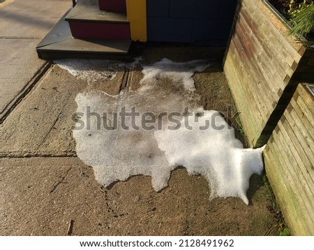 A patch of snow on a mostly cleared sidewalk.