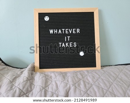 A sign saying whatever it takes. The felt sign has removable letters than can be moved around to make whatever words or saying one wants. 