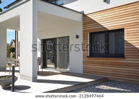 Modern house with wooden cladding, white walls, windows, terrace and door, in summer sunny day, Austria, model house